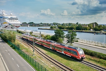 Ein Talent der Baureihe ET 442 der DB Regio Nordost fährt bei der S-Bahn Rostock als S1 von Warnemünde nach Rostock Hbf. Im Hintergrund ein Kreuzfahrtschiff am Warnemünder Passagierkai.