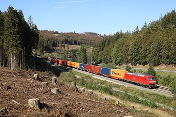 Über den Frankenwald rollt bei Steinbach am Wald ein Containerzug mit einer DB Cargo Ellok der Baureihe 145.