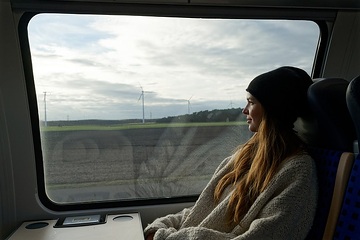 Auf der Reise mit der Bahn - hier: Ausblick auf Landschaft mit Windrädern aus einem Regionalexpress der DB Regio