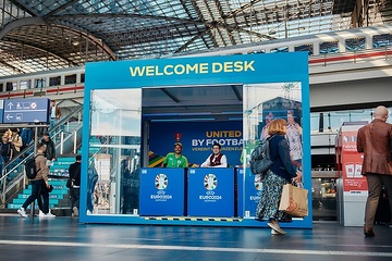 Fußball-Europameisterschaft 2024 - Welcome Desk mit DB Mitarbeiter und UEFA Volunteers im Berliner Hauptbahnhof.